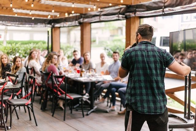 An inspiring moment: A speaker addresses a group during a corporate retreat, as attendees listen attentively and enjoy drinks in a relaxed setting.