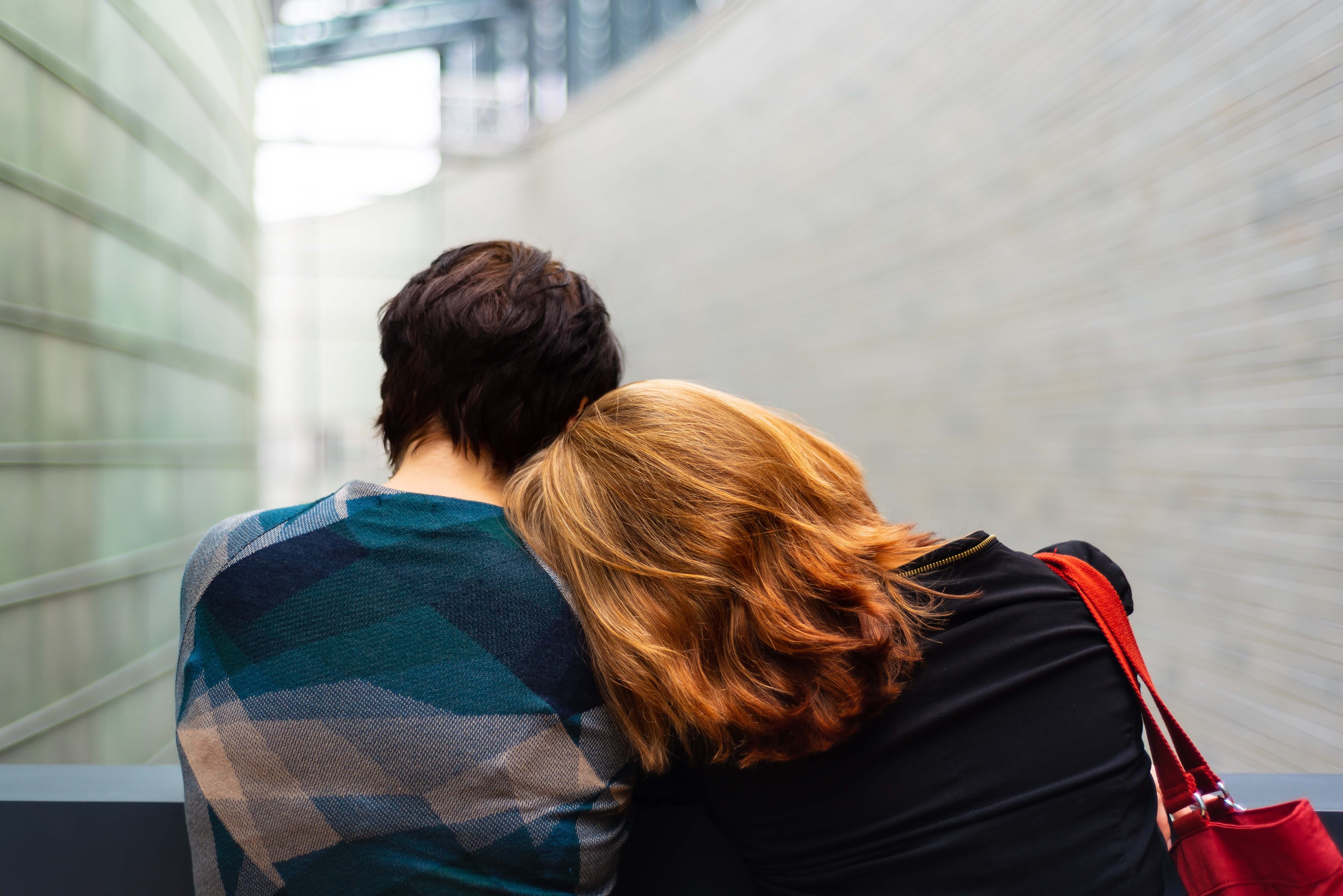 Zwei Frauen legen sich den Kopf an die Schultern.